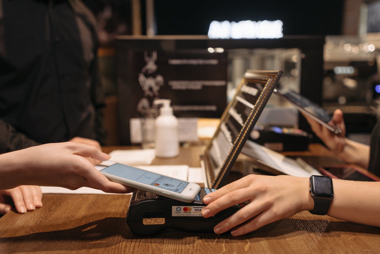 about-us Hands using mobile for contactless payment at café terminal.
